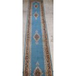 A blue ground Persian Kirman runner with 5 stylised medallions to the centre 236" x 36" There is