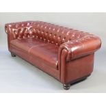 A Chesterfield upholstered in brown buttoned material raised on bun feet