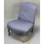 A Victorian nursing chair with blue loose cover, raised on turned and fluted supports, frame