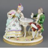 A 20th Century German porcelain figure group of a seated lady and gentleman 10" This lot is in