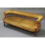 A Victorian carved walnut show frame sofa upholstered in yellow material, raised on turned