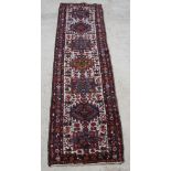 A blue, red and white ground Persian Heriz runner with 7 stylised medallions to the centre 131" x