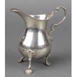 A George III silver cream jug of baluster form with S scroll handle on shell feet, rubbed date