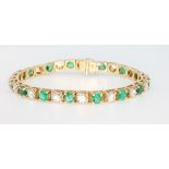 An 18ct yellow gold diamond and emerald bracelet, the brilliant cut diamonds approx. 5ct, the