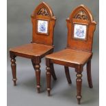 A pair of Victorian mahogany Gothic style hall chairs, the backs inset blue and white tiles with