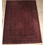 A red ground Bokhara style carpet with 114 octagons to the centre some staining in places 138" x 99"
