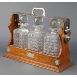 An Edwardian oak and silver plated mounted 3 bottle tantalus 14 1/2" All 3 decanters have chipped