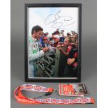 Jenson Button, a coloured photograph standing signing photographs, signed, 11 1/2" x 8" together