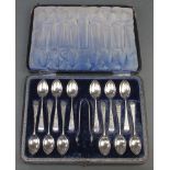 A set of 12 Edwardian silver teaspoons and nips with chased floral decoration in a fitted case