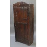 An antique double cupboard of arched form enclosed by panelled doors with iron hinges, constructed