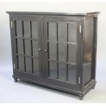 After Rennie Mackintosh, an ebonised rectangular cabinet enclosed by astragal glazed panelled