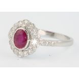 An 18ct white gold ruby and diamond oval cluster ring, the centre stone approx. 0.85ct surrounded by