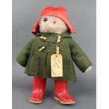 A Paddington Bear complete with red hat and wellington boots and label