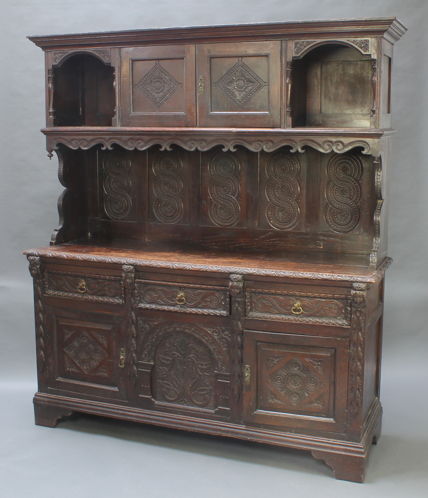 A Victorian heavily carved dark oak dresser, the upper section with moulded cornice and cupboard