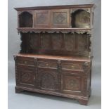 A Victorian heavily carved dark oak dresser, the upper section with moulded cornice and cupboard