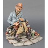 A Capodimonte group of a seated umbrella maker, signed Volta 10" The hat is slightly chipped