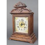 An Ansonia 8 day striking clock with silvered dial and Arabic numerals contained in an oak arch