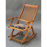 An Edwardian walnut stick back rocking campaign chair The pads to the arms are missing