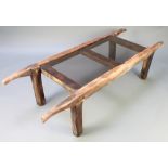 A rectangular elm and smoked plate glass coffee table, formed from trestles 17"h x 68"w x 24"d There