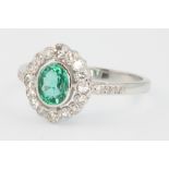 An 18ct white gold emerald and diamond oval cluster ring, the centre stone approx 0.75ct, size P