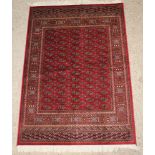 A red ground Bokhara style carpet with 65 octagons the centre 75" x 53"