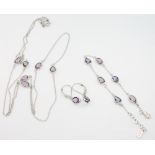 A silver necklace with purple stones together with a bracelet and pair of matching earrings