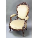 A Victorian heavily carved mahogany show frame open arm chair upholstered in green Dralon raised