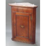 A Georgian mahogany corner cabinet with moulded cornice, fitted shelves enclosed by a panelled