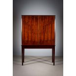 A ROSEWOOD UPRIGHT TWO DOOR SIDE CABINET, 1960s, revealing a shelved interior, the base with