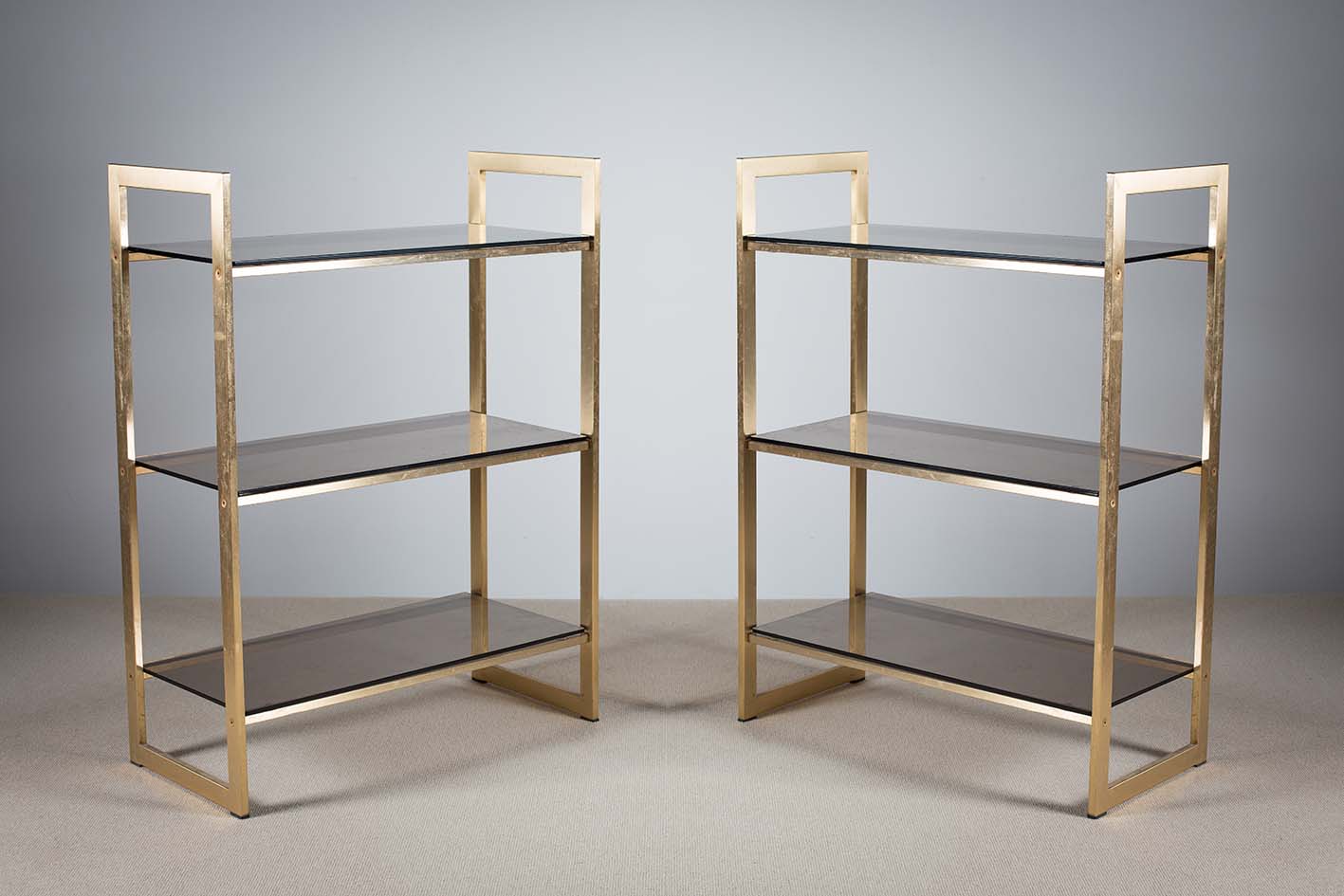A PAIR OF GILT THREE TIER OPEN SHELVES, 1970s, with angular supports, 75cm (w) x 50cm (d) x 100cm (