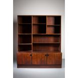 A ROSEWOOD BOOKCASE, DANISH, the open shelved superstructure on a base with three cupboard doors,