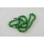 A STRING OF POLISHED APPLE GREEN JADE BEADS, 30 ins long.