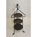 AN EARLY 20TH CENTURY ART NOUVEAU PERIOD WROUGHT IRON THREE TIER CAKE STAND with beaten copper