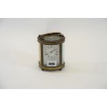 AN EARLY 20TH CENTURY OVAL BRASS 8 DAY CARRIAGE CLOCK with white enamel dial, raised on turned feet,