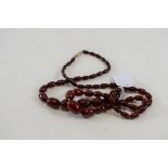 A LATE VICTORIAN STRING OF GRADUATED RED AMBER BEADS, 16 ins long and a similar DITTO STRING,