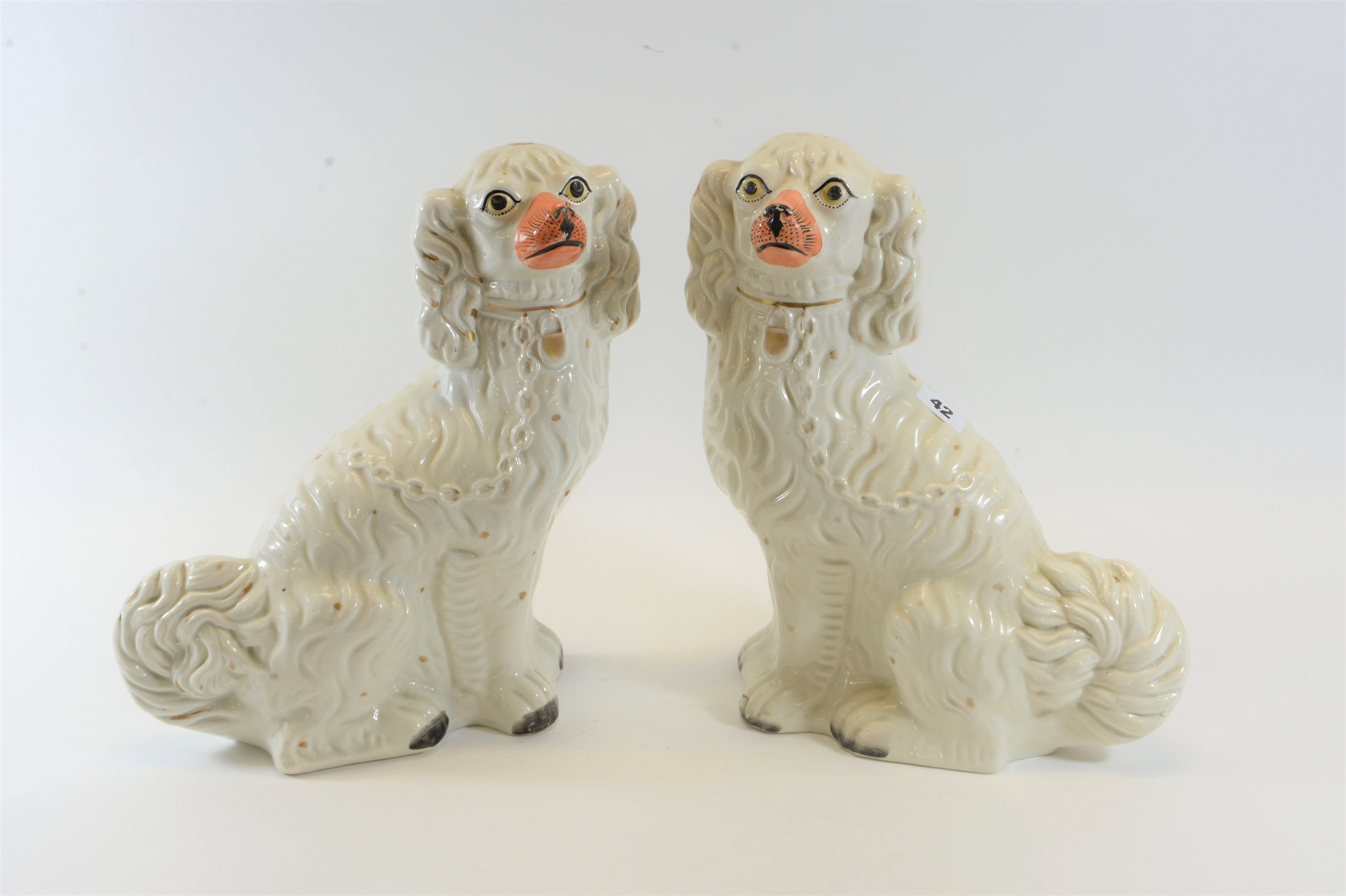 A PAIR OF 19TH CENTURY WHITE GLAZED STAFFORDSHIRE SPANIEL DOGS with painted eyes and muzzles and