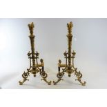 A PAIR OF FRENCH EMPIRE STYLE ORMOLU CHENETS of rococo influence with flambe finials,