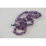 A LONG STRING OF OVOID HAND WORKED AMETHYST BEADS, 44 beads in total, 36 ins long.