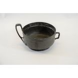AN EARLY 20TH CENTURY TUDRIC PEWTER BOWL with elongated loop handle and side handle, stamped TUDRIC,