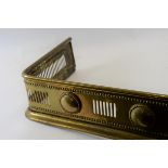 AN EDWARDIAN BRASS FENDER with pierced roundel decoration, 42 1/2 ins long.