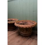A PAIR OF REPRODUCTION CIRCULAR TERRACOTTA URNS with basket weave sides and turn over rims,