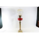 AN EDWARDIAN STYLE BRASS CORINTHIAN COLUMN TABLE OIL LAMP with ruby glass fount and duplex burner,