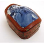 A Chinese shaped red lacquered box and cover with gilt decoration and blue and white ceramic panel
