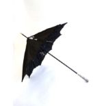 A black silk ladies parasol with ebonised shaft and white metal handle having embossed figural