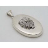 A silver pendant of locket form with owl decoration.