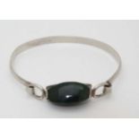 A silver bracelet of bangle form set with polished green jade like hardstone CONDITION: