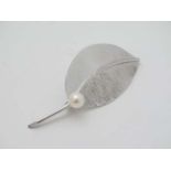 A silver brooch of stylised leaf form set with pearl.