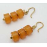 A pair of yellow metal drop earrings set with amber coloured roundel beads. Indistinctly marked.