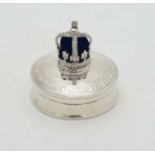 A white metal pill box with hinged lid surmounted by a crown.