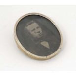 A white and gilt metal brooch of locket form containing a photographic portrait miniature of a